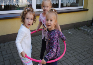 trzy młosze dziewczynki stoją w kole hula-hop na tarasie